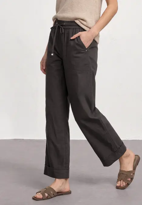 Beige kurzes Top mit schwarzen, weiten Hosen und braunen Sandalen.