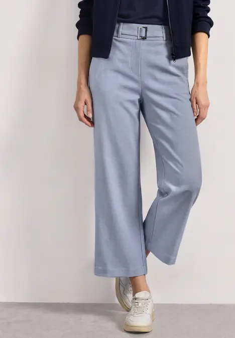 Hellblaue, hoch taillierte Culotte-Hose mit Gürtel und weißen Sneakern.
