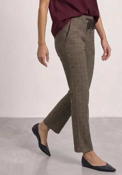 Schlanke braune karierte Hose kombiniert mit schwarzen spitzen Ballerinas.