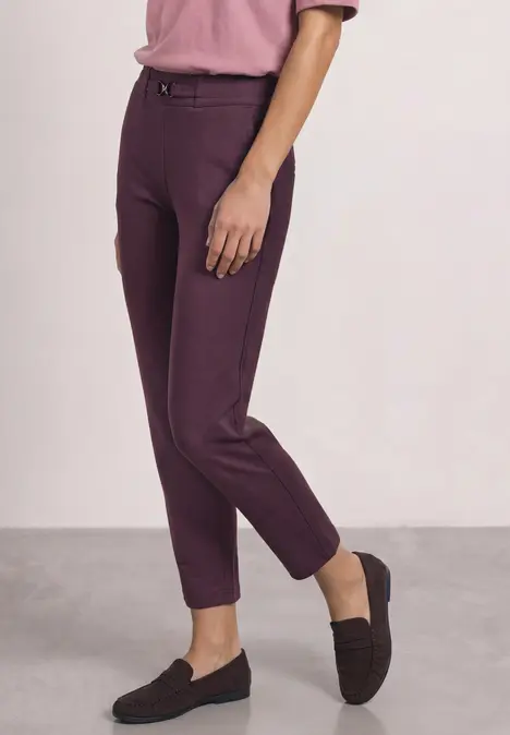 Eine Person trägt schmal geschnittene, violette Hose und schwarze Loafers.