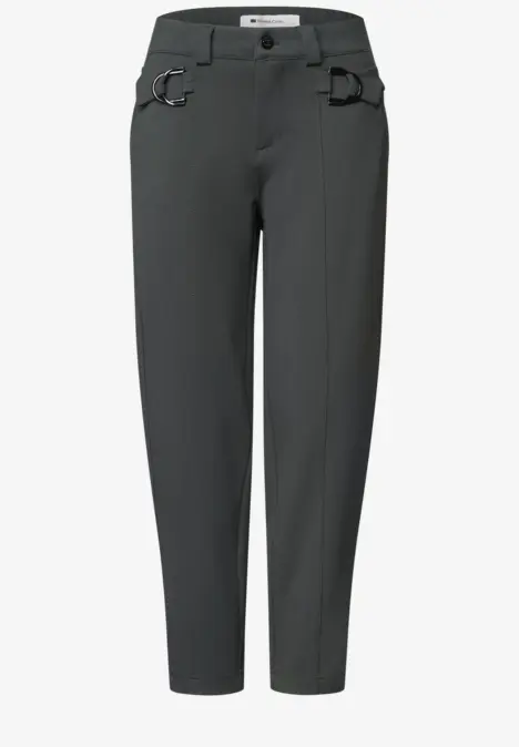 Dunkelgraue, lässige Hose mit leicht zulaufenden Beinen, Gürtelschlaufen und markanten Metallringen an den Taschen.