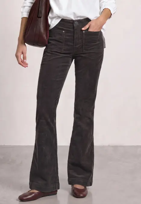 Schwarze Cordhose mit ausgestelltem Bein, hoher Taille, Taschen- und Nahtdetails, kombiniert mit braunen Loafers.