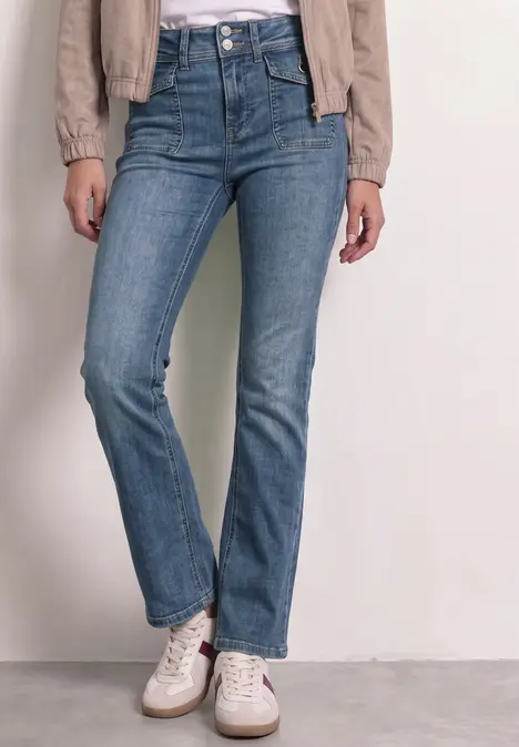Eine Person trägt gerade geschnittene blaue Jeans und weiße Sneaker.
