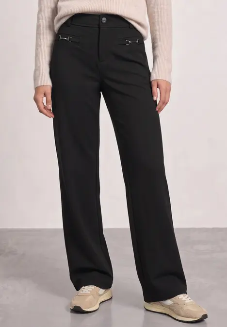 Pantalon droit noir pour femme associé à des baskets confortables.