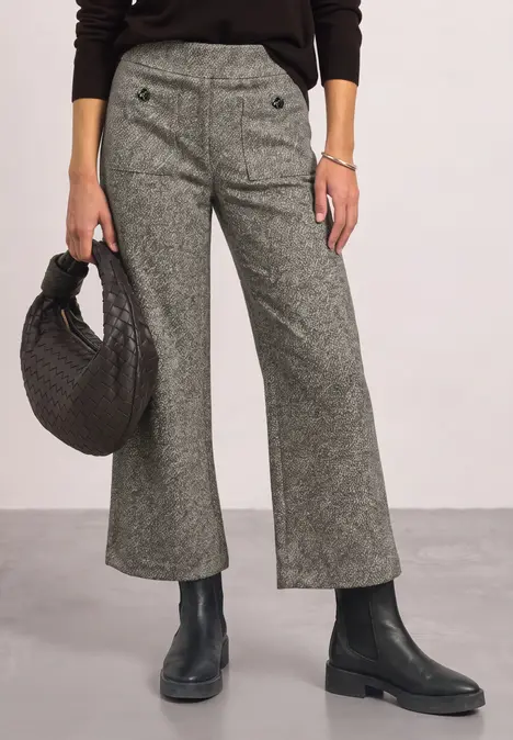 Graue, weit ausgestellte Hose mit Knopfdetail, schwarzer Handtasche und schwarzen Stiefeln.