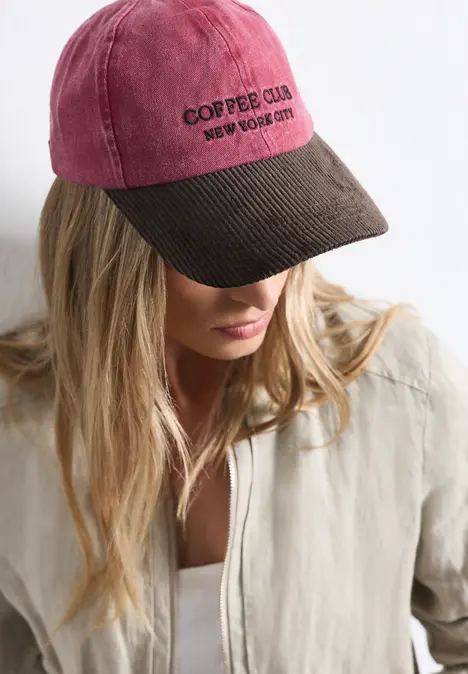 Frau mit blonden Haaren trägt zweifarbige Baseballcap mit Aufschrift "COFFEE CLUB"