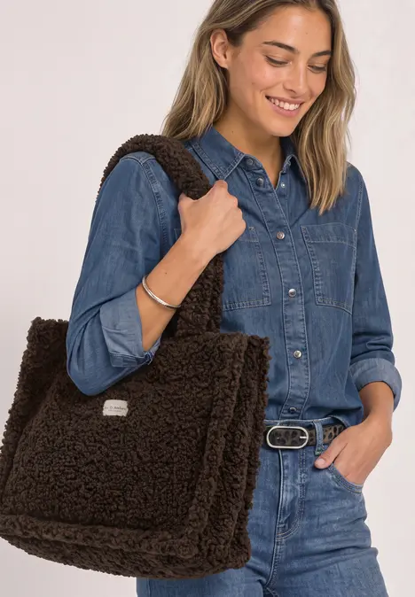 Frau in Jeans-Outfit mit großem flauschigem braunen Schulterbeutel