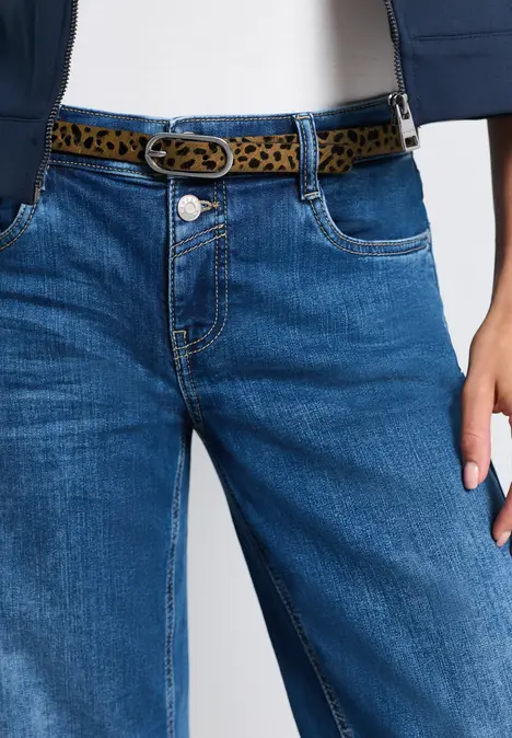 Frau trägt blaue Jeans mit Leopardenmuster-Gürtel und weißem Top