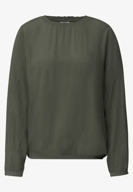 Blouse unie vert olive à manches longues et encolure ronde.