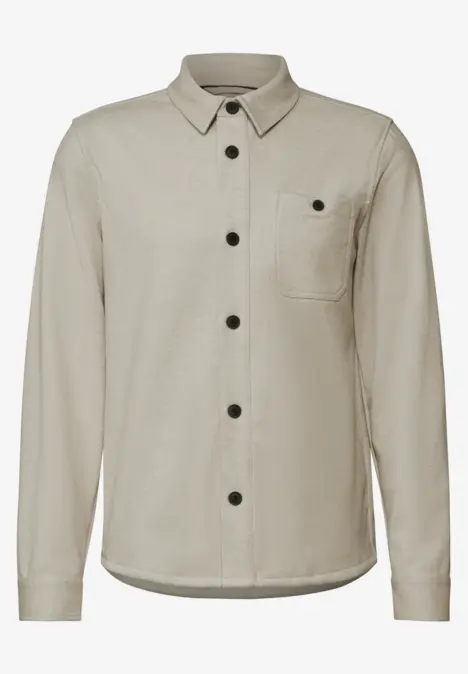Beige Hemdjacke mit schwarzen Knöpfen und Brusttasche.