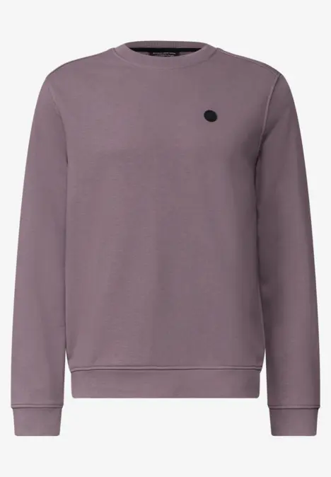 Sweat-shirt violet à col rond, manches longues, poignets côtelés et petit patch logo noir discret sur la poitrine.
