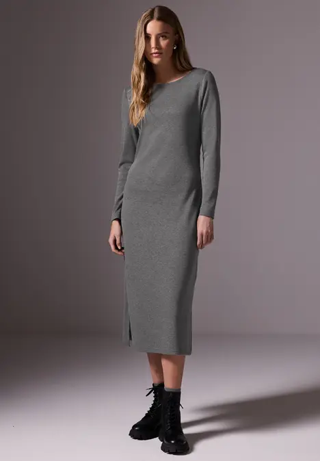 Frau in grauem, langem Kleid mit langen Ärmeln und schwarzen Stiefeln.