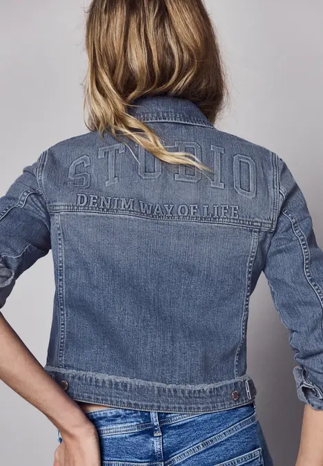 Persoon van achteren in blauwe jeansjas met opschrift 'G-STAR DENIM W.O.H.B.'