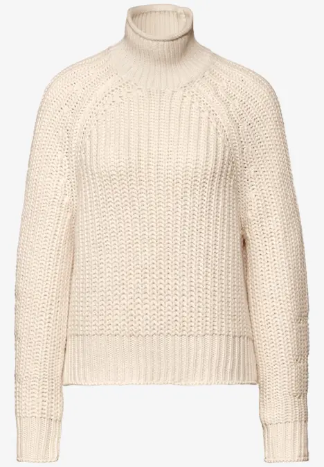 Beiger Strickpullover mit Rollkragen und grobem Muster.