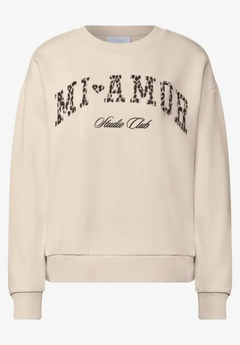 Sweatshirt beige avec inscription léopard 'MI+AMOR' et petit texte dessous.
