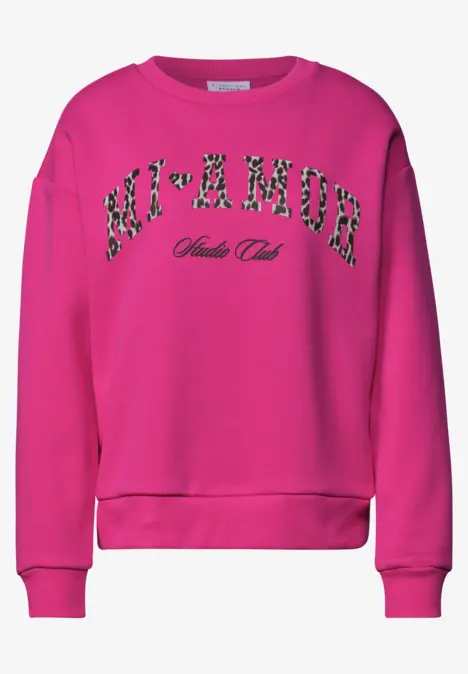 Ein pinkfarbener Sweatshirt mit floral gemustertem Schriftzug "M'AMOUR" auf der Vorderseite.
