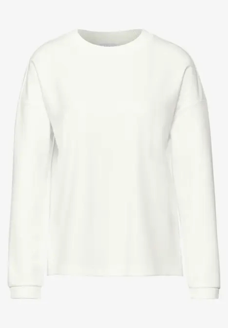 Ein schlichter, weißer Pullover mit langen Ärmeln.