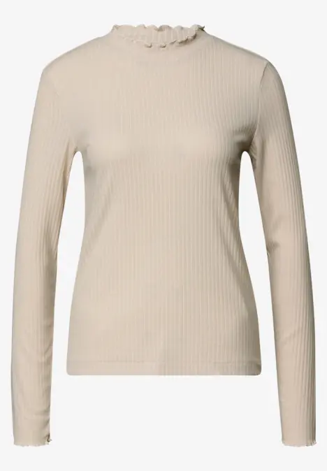 Haut côtelé beige à manches longues avec dentelle froufroutante au col et aux poignets.