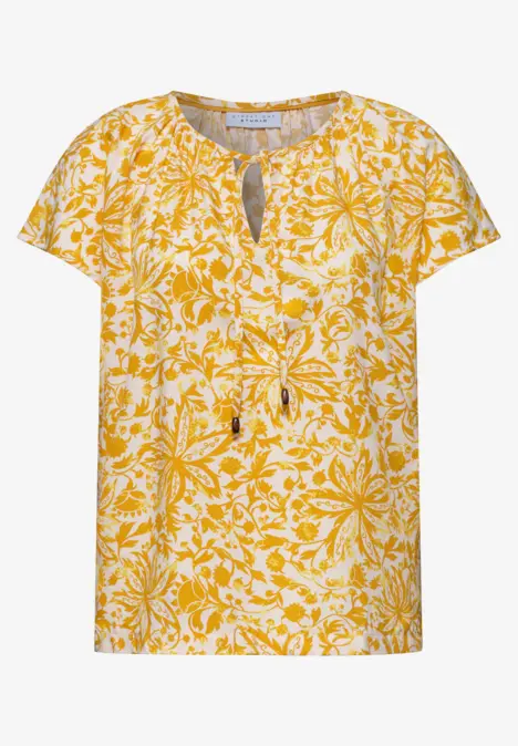 Top femme jaune clair à motif floral blanc, manches courtes, encolure ronde avec fente.