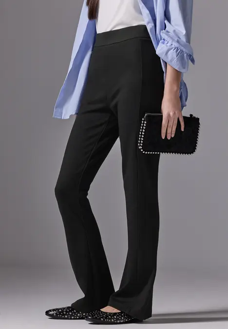 Frau mit schwarzer Hose, hellblauer Bluse und Nietenhandtasche.