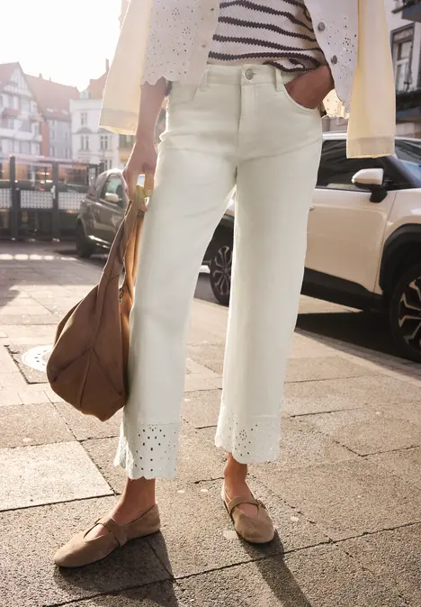 Witte cropped jeans met geborduurde zoom, gecombineerd met loafers, gestreept shirt en ruime handtas.