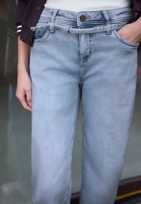Lichtblauwe jeans, losse pasvorm, handen in de zakken.