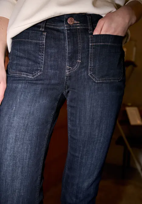Close-up van een persoon in donkerblauwe jeans, hand in het voorvak.