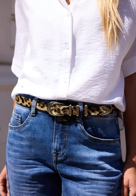 Witte blouse en blauwe jeans met een opvallende luipaardprintriem.